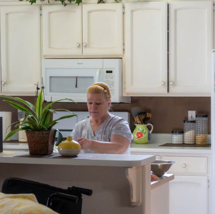 A professional caregiver prepares a fresh meal in a clean, modern kitchen at Guardian Angel Home Care. The facility focuses on providing home-cooked meals and a hands-on, family-oriented environment for its residents.
