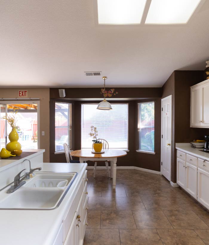 A clean, well-lit residential kitchen at Guardian Angel Home Care II featuring white cabinetry, a gas stove, a white refrigerator, and a warm, home-like environment for preparing fresh meals